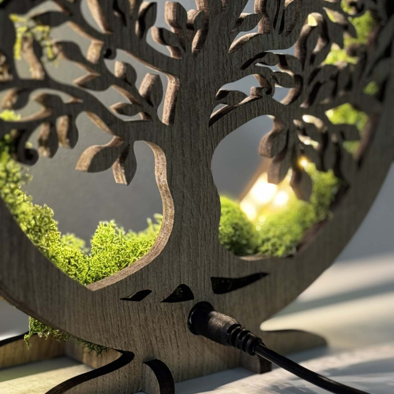 O vedere de aproape a unui Copac al Vieții din lemn, iluminat din spate, înconjurat de mușchi.